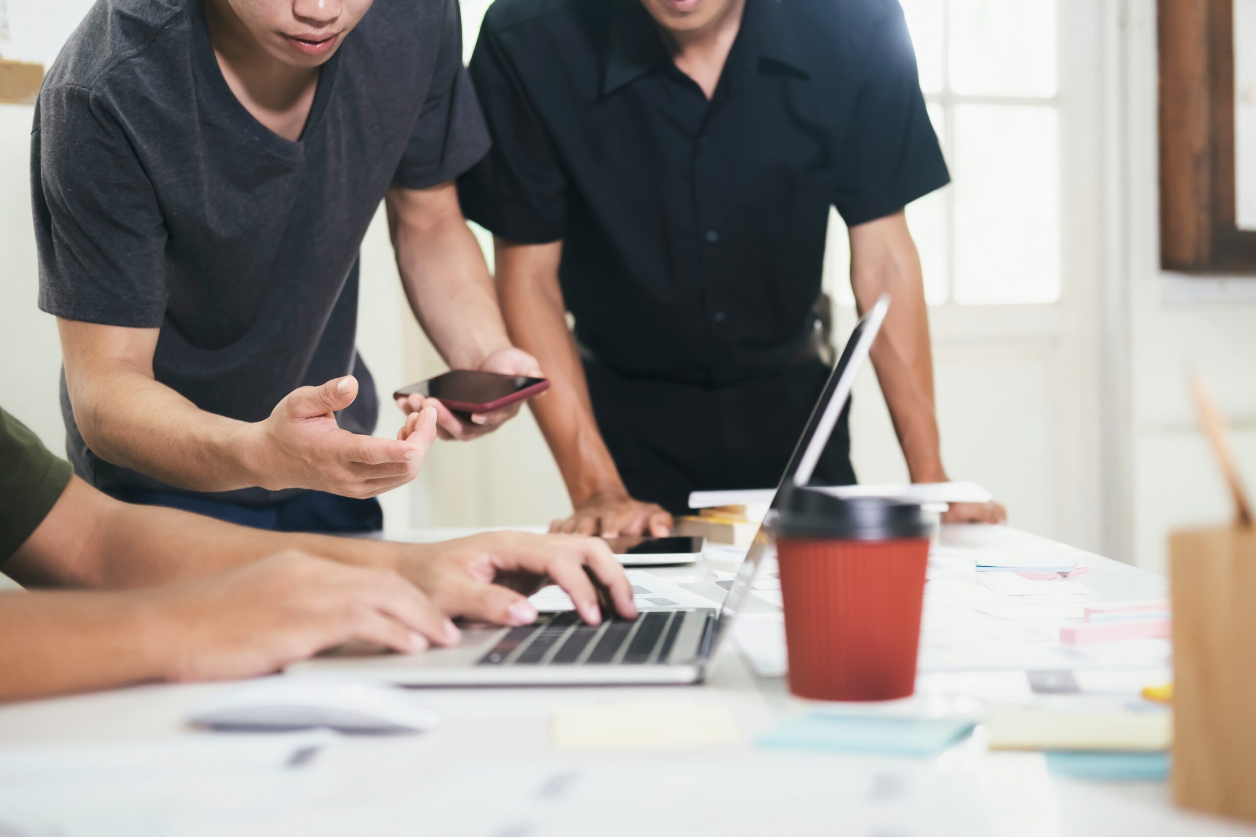 A group of people looking at a laptop, discussing the cyber security tip of regular software updates.