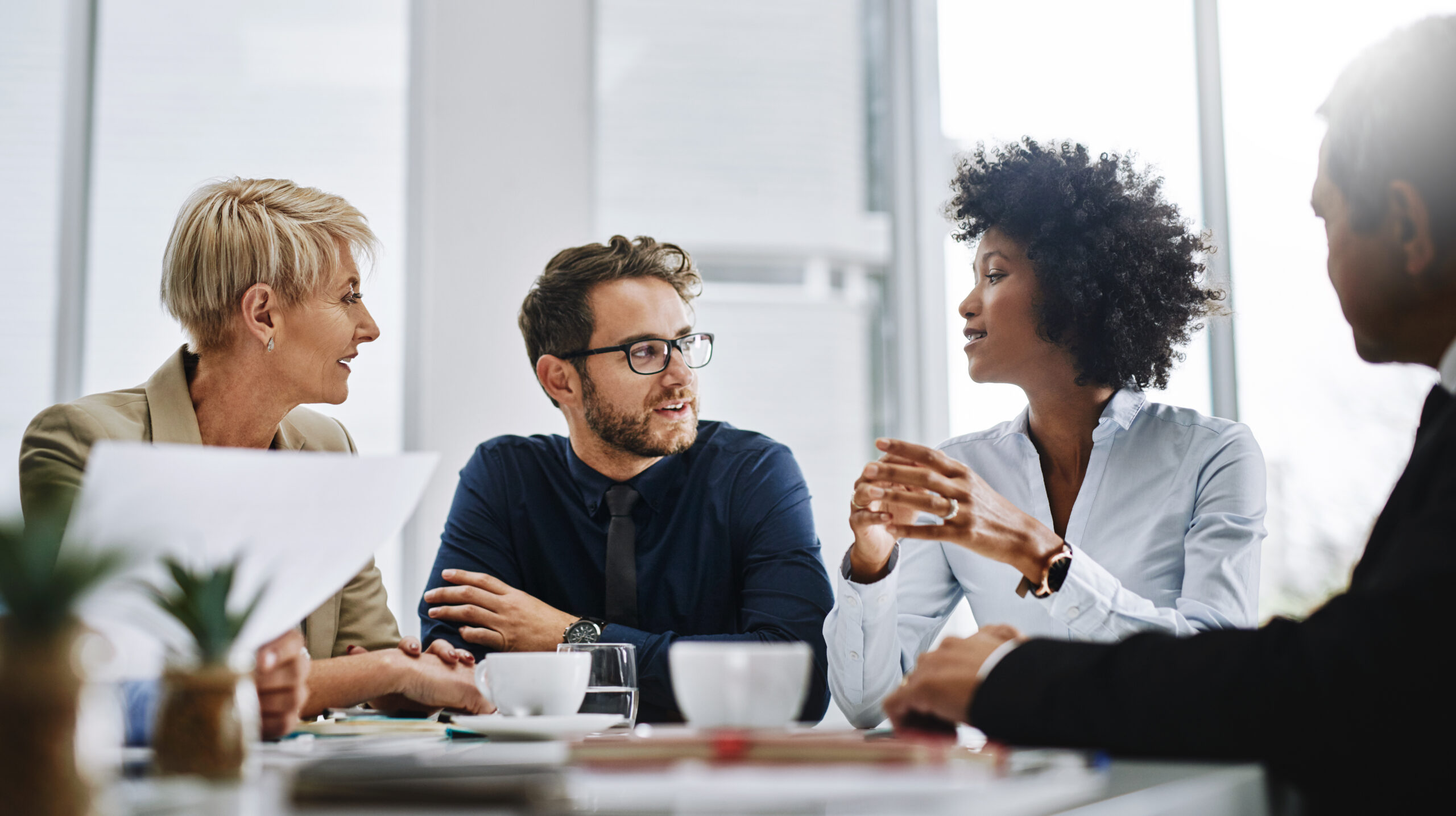 Four professionals are having a discussion around a table in a modern office setting, exploring what is business process automation.