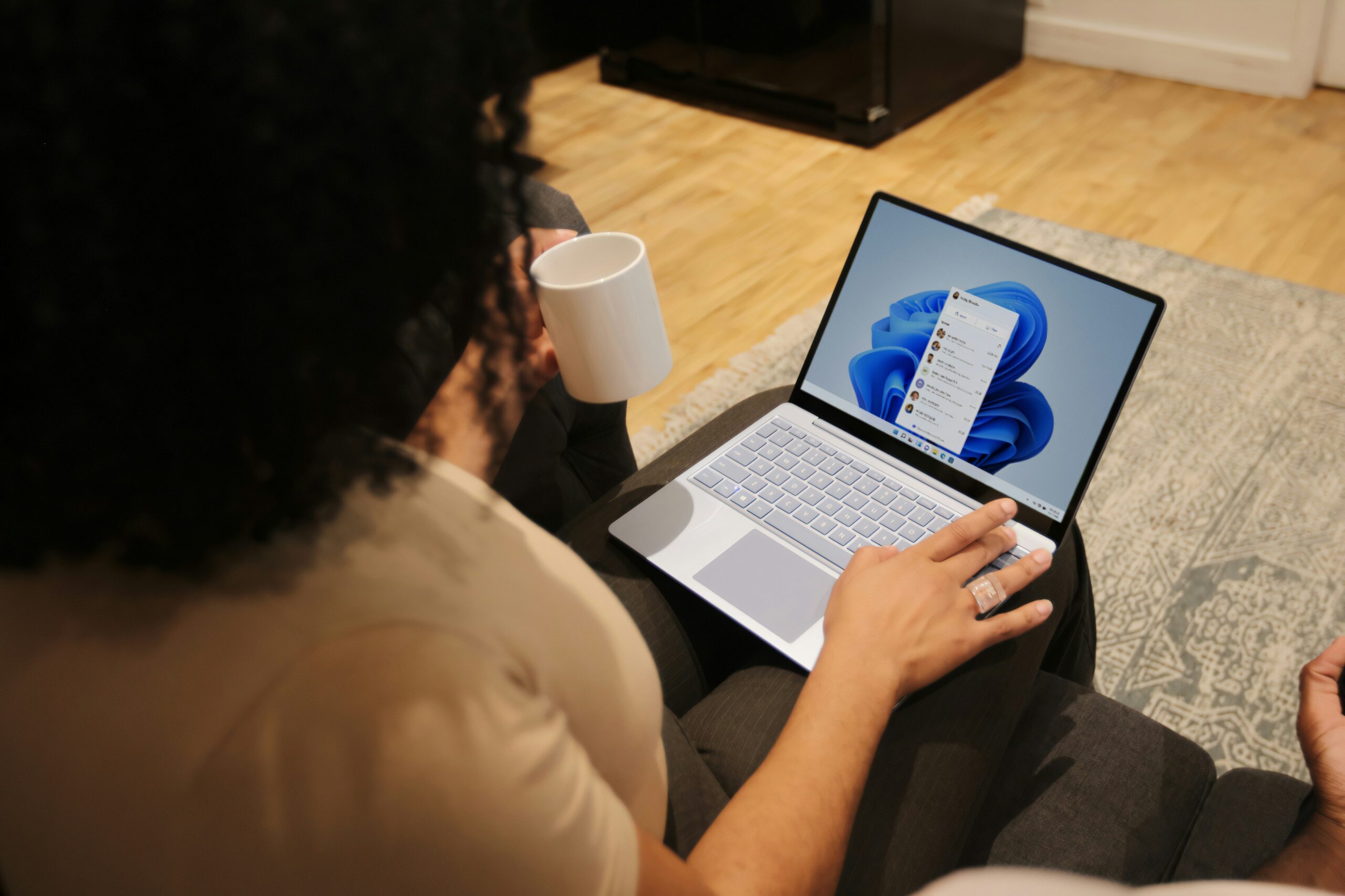 Person holding a white mug while using a laptop to research what is Office 365 used for.