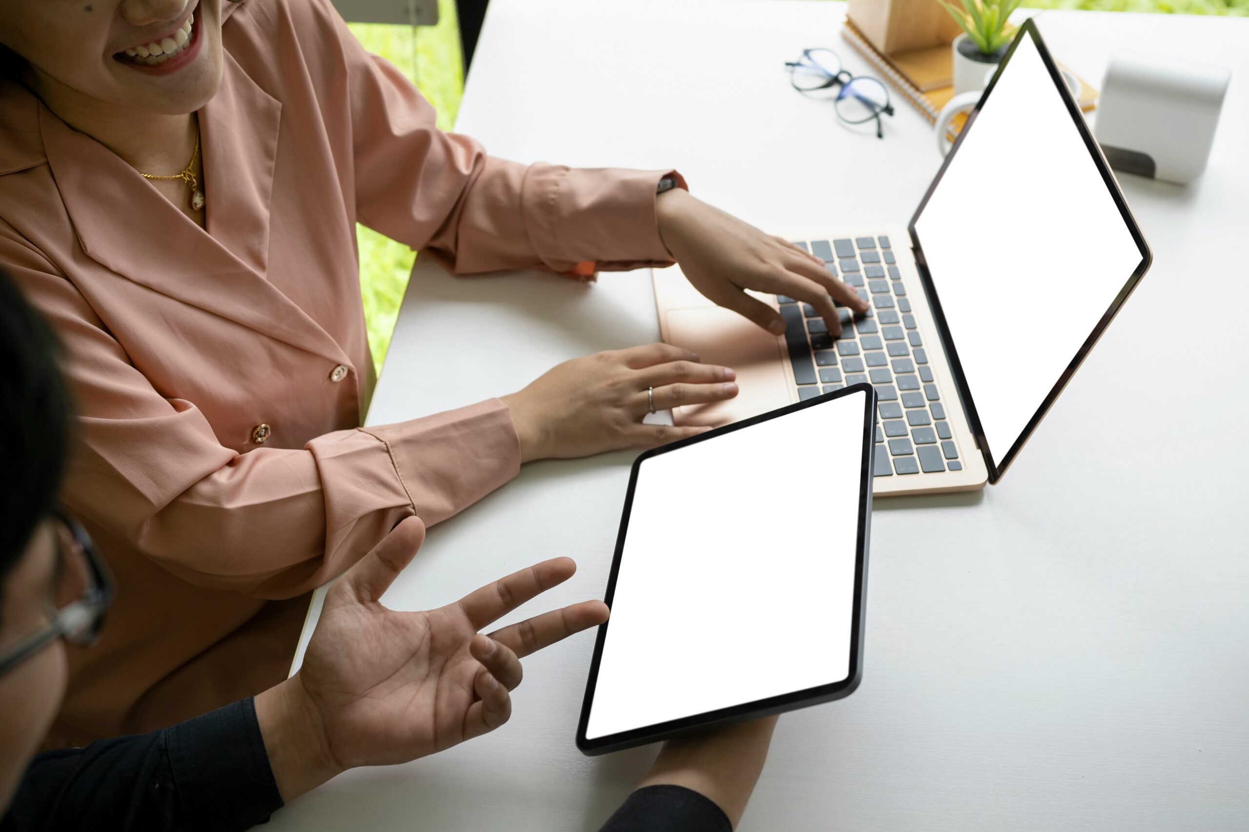 Two people sitting at a desk, each using a device to research what Office 365 is and what it is used for.
